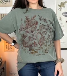 🍄 Hand-drawn, intricate nature design exclusively from PoohBearCo 🍄 Cottagecore forestcore aesthetic with squirrel, mushrooms, wildflowers, and botanicals. 🍄 Comfort Colors brand, 100% garment-dyed ringspun cotton. 🍄To ensure sizing, refer to size chart in photos and compare measurements to those of a sweatshirt you already own that fits well. 🍄 Non-toxic, eco-friendly, water-based inks safer for you & the environment. Forestcore Aesthetic, Cabin Art, Pretty Shirts, Floral Tee, Granola Girl, Comfort Colors Shirt, Retro 70s, Rustic Cabin, Nature Design