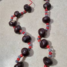 two necklaces made out of wood beads and red, gray and blue beads on a marble surface