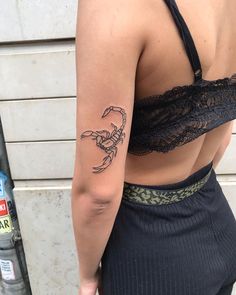 a woman with a scorpion tattoo on her left arm and right arm behind her back