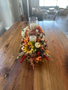 an arrangement of flowers and candles on a wooden table