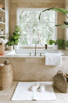 a bath room with a tub and a sink next to a window in front of a potted plant