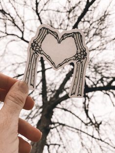 someone is holding up a sticker with a heart in the shape of a skeleton