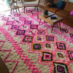 a living room filled with furniture and a pink rug