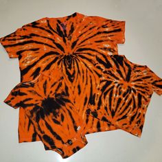 three orange and black tiger print shirts laying on top of each other in front of a white background