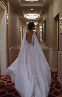 a woman in a wedding dress is walking down the hallway with her back to the camera