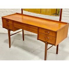 a wooden desk with two drawers and a mirror behind it