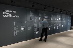 a man standing in front of a black wall with white writing and pictures on it