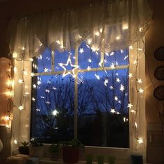 the window is decorated with white lights and snowflakes hanging from it's side