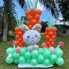 an inflatable bunny is sitting on top of some carrots and grapes with balloons attached to it