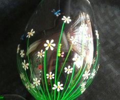 a glass vase with flowers painted on the bottom and green stems sticking out of it