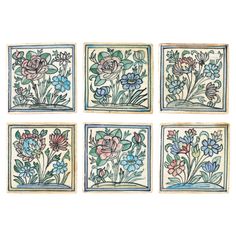 four tiles with flowers and leaves on them, each painted in blue and pink colors