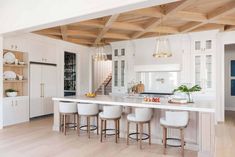 a large kitchen with white cabinets and counter tops, along with stools at the island