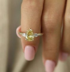 a woman's hand holding a yellow diamond ring