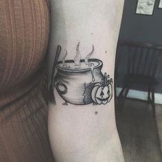 a woman's arm with a pot and pumpkins tattoo on the left forearm