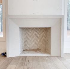 an empty room with a white fireplace and wood floors