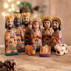 a group of figurines sitting on top of a wooden table next to a pine cone