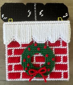 two crocheted christmas stocking holders on a wooden surface, one with a green wreath and the other with a red bow