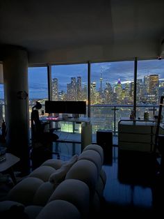 a living room filled with furniture and large windows overlooking the city at night in front of them