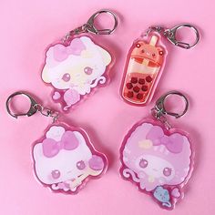 four hello kitty keychains on a pink background