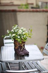 a small potted plant sitting on top of a table next to a pair of boots