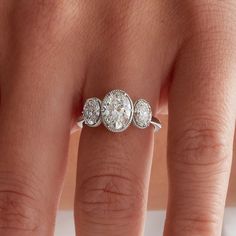 three stone diamond ring sitting on top of someone's finger