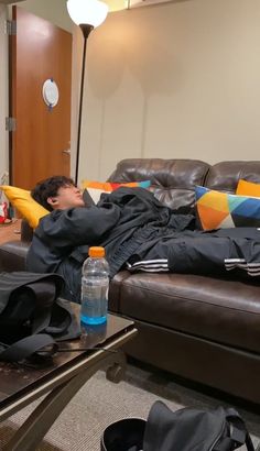 a man laying on top of a couch in a living room next to a table