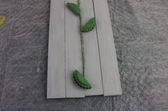 two green flowers are placed on a piece of white wood with some string attached to it