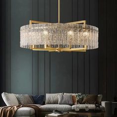 a living room with a couch, coffee table and chandelier hanging from the ceiling