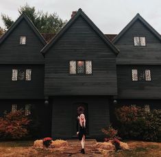 a woman standing in front of a black house