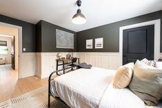 a bedroom with black and white walls, wood flooring and a bed in the middle