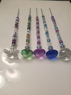 seven glass bead necklaces lined up on a white counter top, each with different colored beads