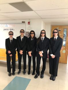 a group of people in suits and sunglasses standing next to each other on a tile floor