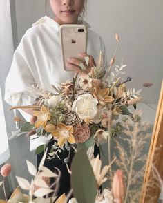 a woman taking a selfie in front of a mirror holding a cell phone and flowers