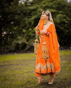 a woman in an orange and gold outfit is blowing bubbles into the air while standing on grass