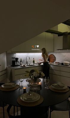 a woman is standing at the kitchen counter in front of an oven and dining table