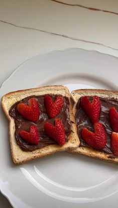 two pieces of toast with chocolate spread and strawberries on them sitting on a plate