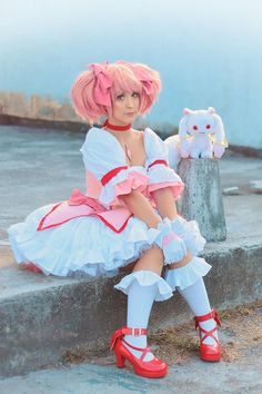 a woman in a pink and white dress sitting on steps with a stuffed animal next to her