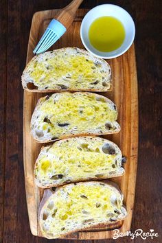 four pieces of bread with cheese and olives on them next to a bowl of oil