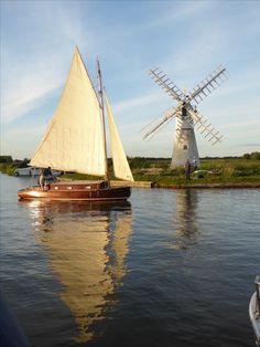 a small sailboat in the water next to a windmill