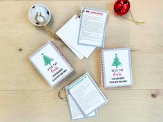 four christmas cards on a wooden table next to a red ornament and ribbon