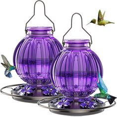 two purple vases sitting on top of each other with hummingbirds flying around them