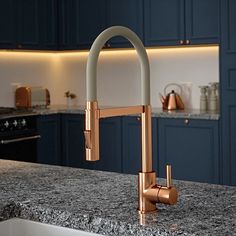 a kitchen sink with a faucet and marble counter top in front of blue cabinets