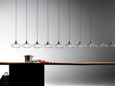 a long table topped with lots of hanging glass globes over it's head