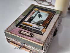 an altered box is sitting on a table next to a candle and some branches in the background