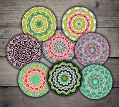 six circular coasters with colorful designs on wooden table top, all in different colors and sizes