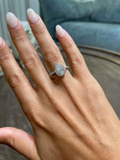 a woman's hand with a diamond ring on top of her left hand, sitting on a couch