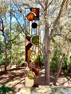 a tall stained glass window sitting in the middle of a forest with trees behind it