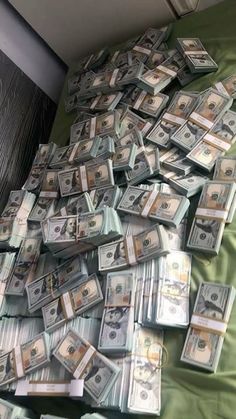 a pile of money sitting on top of a green bed spread out in front of a window