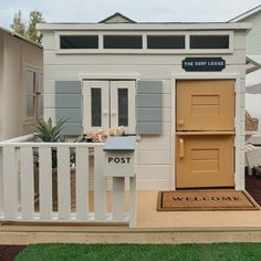 a small white building with two doors and a welcome mat on the front lawn area