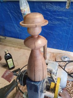 a wooden man with a hat on top of a table next to other woodworking tools